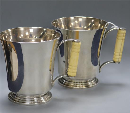 A pair of Art Deco silver mugs with turned ivory handles and flared rims, Adie Bros. Birmingham, 1934, gross 21 oz.